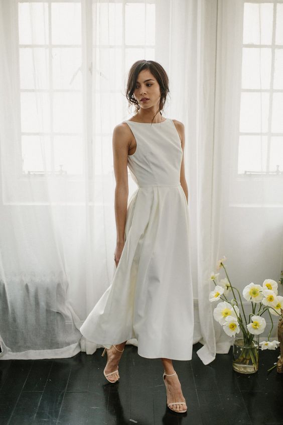 a casual midi wedding dress with a high neckline, no sleeves and a pleated skirt plus minimalist shoes for a casual wedding