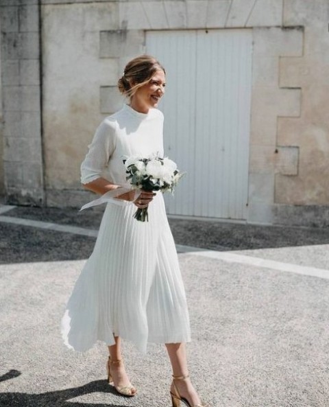 a casual wedding look with a plain pleated white midi dress with long sleeves and metallic shoes to brighten up the look