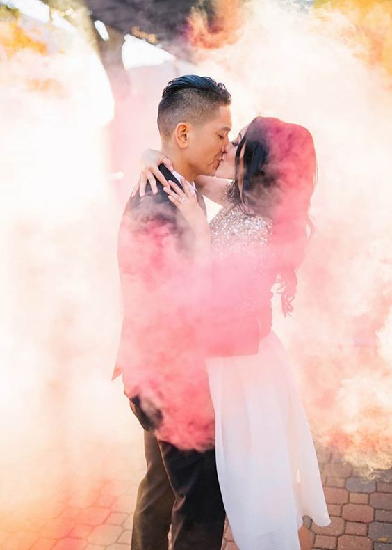 a couple kissing in colorful smoke is a great and veyr emotional wedding portrait idea