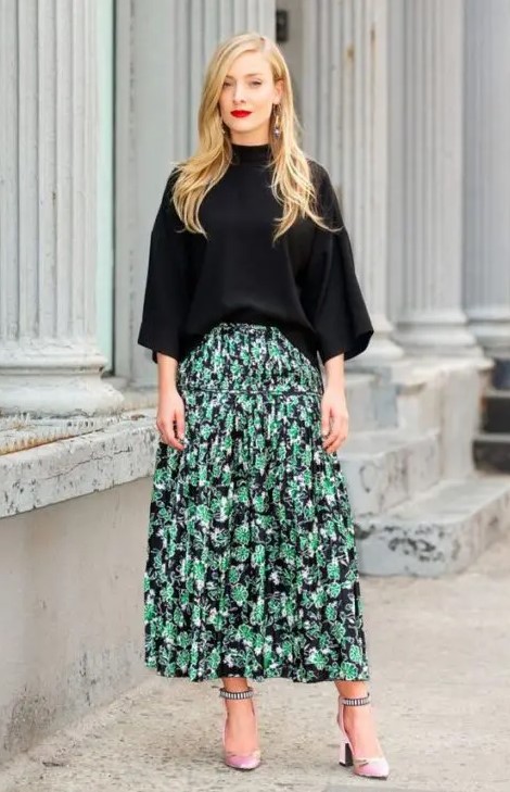 a fall wedding guest outfit with a black top with wide sleeves, a black green floral print midi skirt, pink shoes