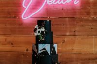 a fantastic black rock n roll wedding cake with gold touches, fresh blooms and geometric detailing is amazing