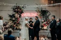 a fantastic wedding ceremony space with lots of candles, lush blooms and greenery and a neon sign