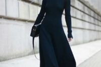 a gorgeous black fitting midi dress with cutout shoulders and long sleeves, black boots, statement earrings and a black bag