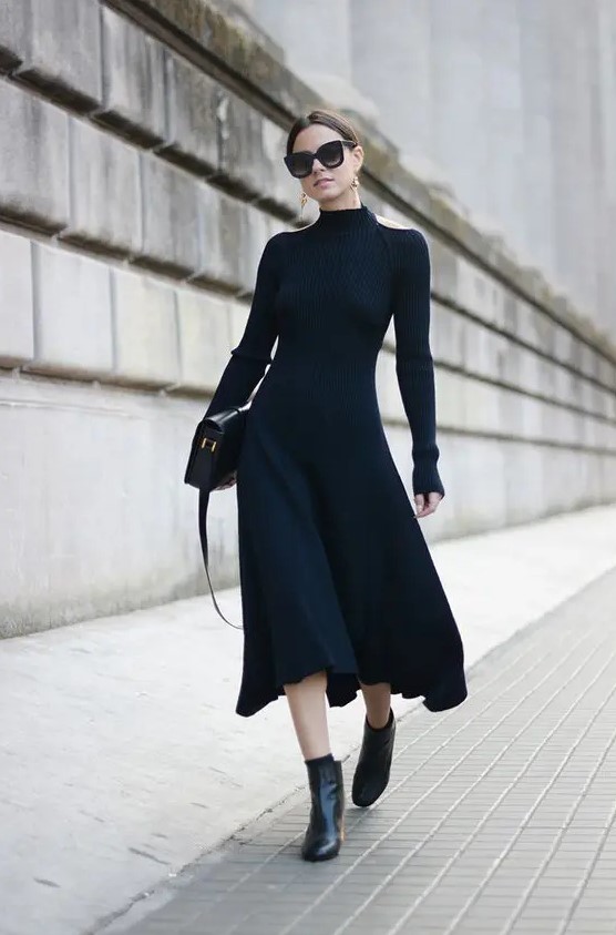 a gorgeous black fitting midi dress with cutout shoulders and long sleeves, black boots, statement earrings and a black bag