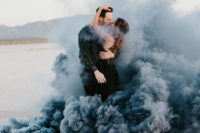 a gorgeous engagement photo of a couple in black standing in black smoke in a desert just wows