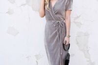 a grey wrap velvet dress with long ties, short sleeves, nude heels and a small black bag