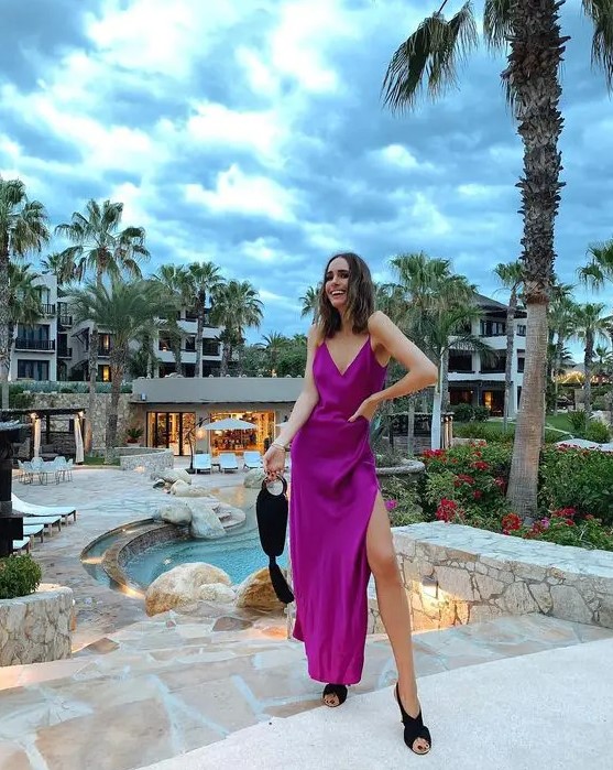 a hot purple silk maxi dress with a side slit, black criss cross shoes and a black bag with a tassel
