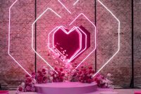 a jaw-dropping wedding ceremony space with neon hearts, pink, fuchsia and blush blooms, matching floral arrangements along the aisle