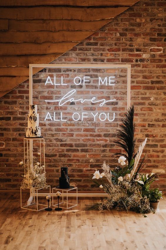 a lovely backdrop of a grame with a neon sign, greenery and neutral blooms is amazing