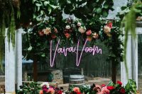 a modern wedding reception space with greenery, pink and neutral blooms and a pink neon sign is awesome