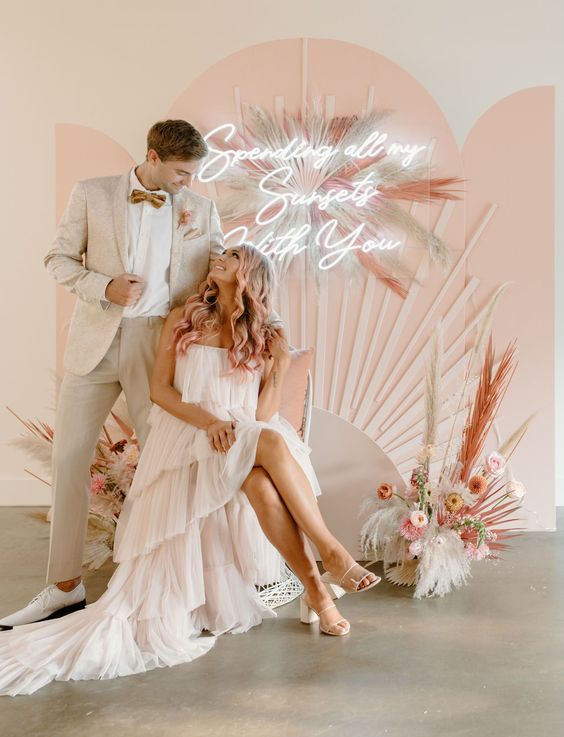 a pastel wedding backdrop with pampas grass, pink blooms, a neon sign is a cool idea for a pastel boho wedding