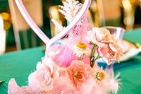 a pink wedding centerpiece of pink blooms, feathers, rocks, a neon heart sign is a cool and fun solution for a pink wedding