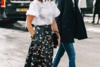 a pretty wedding guest look with a white shirt with short sleeves, a refined black maxi skirt with pink floral prints, black shoes and a black bag