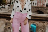 a pretty wedding guest outfit with a polka dot blouse and pink pants, a straw hat and strands of pearls plus statement earrings