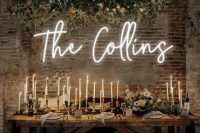 a small wedding reception space with a neon sign and an overhead floral installation is amazing