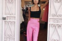 a stylish and catchy wedding guest look with a black crop top and hot pink high waisted trousers with cut out sides is amazing for summer celebrations