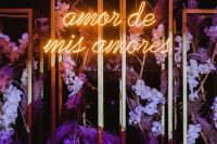 a unique wedding backdrop with purple and lilac blooms and grasses and a neon sign is a gorgeous idea