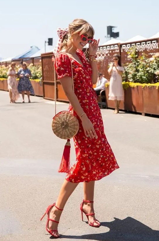 A vintage styled red floral midi dress with short sleeves and a V neckline, red heels and a straw bag