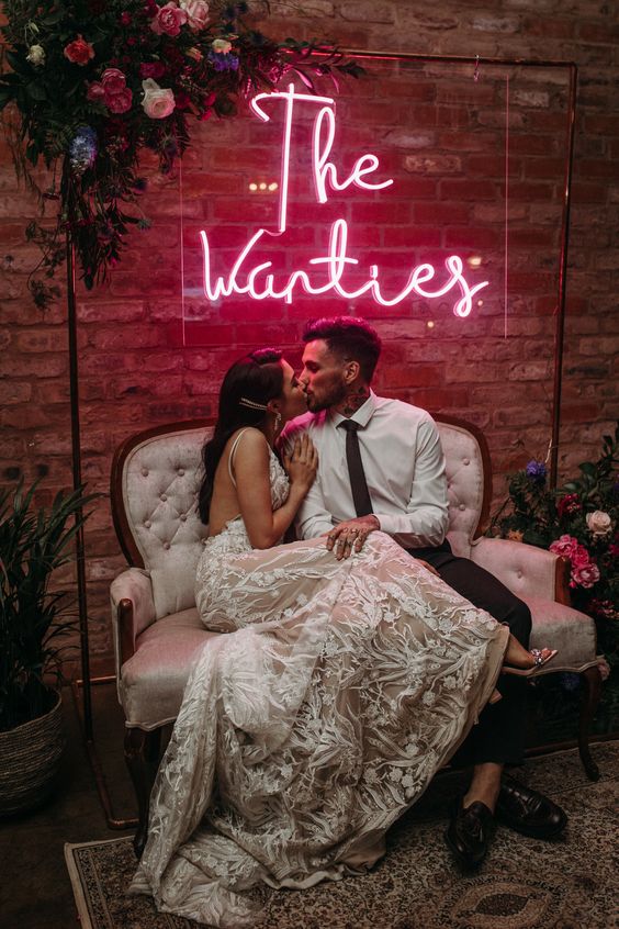 a wedding lounge with a vintage loveseat, bold blooms and a pink neon sign is amazing for a modern wedding
