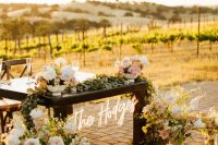 a wedding sweetheart table with white and blush blooms and greenery plus a neon sign is amazing