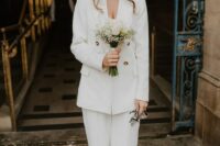 a white bridal pantsuit with a white top, white shoes and a small wedding bouquet are a lovely combo for a wedding