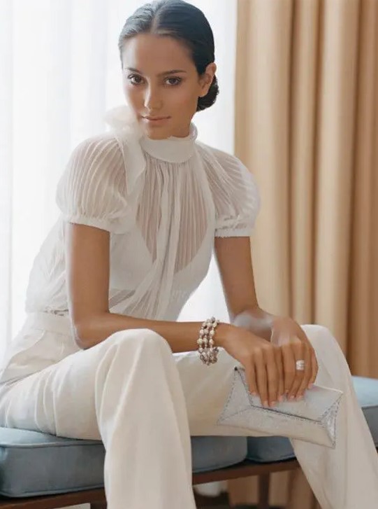 a white jumpsuit with a sheer pleated bodice and short sleeves and plain pants for a modern bride