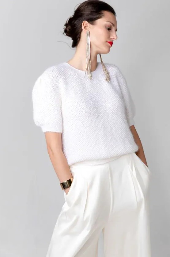 a white knit top with short sleeves, white high waisted wideleg trousers, statement silver earrings and a bracelet for a modern casual bridal look
