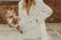 a white pantsuit with a deep neckline, a fedora hat with a veil for a more exquisite look and layered necklaces
