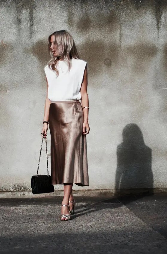 a white top with statement shoulders, an elegant taupe midi slip skirt, silver shoes and a black bag