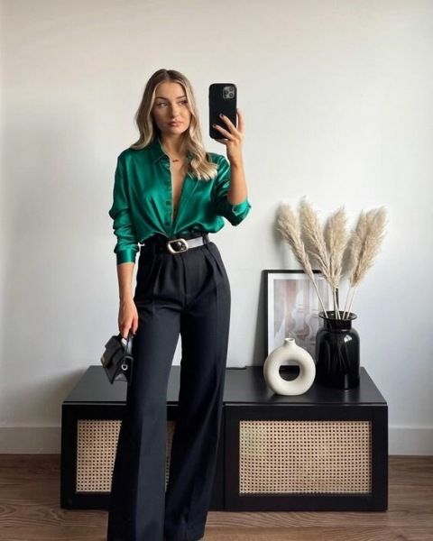 an elegant wedding guest look with an emerald shirt, black high waisted pants, a two-tone belt, a tiny black bag