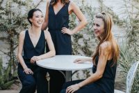 stylish and simple navy modern jumpsuits with deep V-necklines and black heels for modern bridesmaids