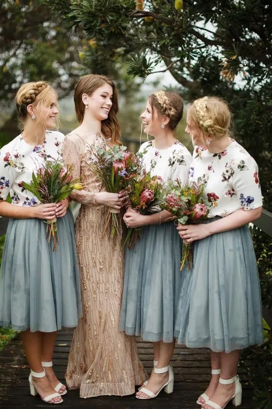 Two piece bridesmaid outfits with floral print tops and sage green midi a line skirts plus white shoes and wildflowers
