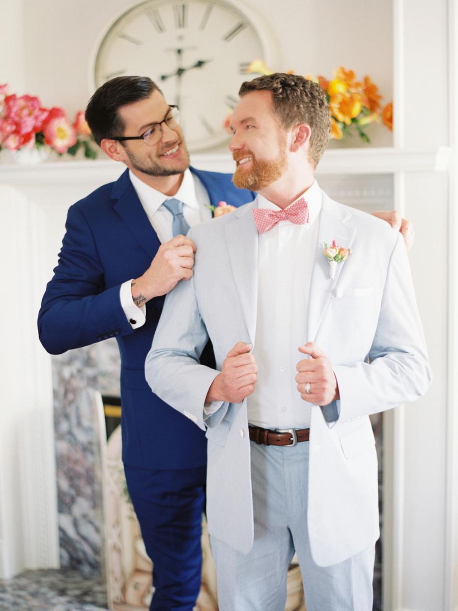 One groom was wearing a light blue suit with a coral bow tie and the other groom was wearign a bold blue suit with a light blue tie