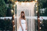 05 a boho wedding arch with string lights, greenery and a macrame hanging is a very trendy and bold idea