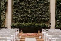 07 The ceremony space was done with candles, a greenery wall and simple white chairs