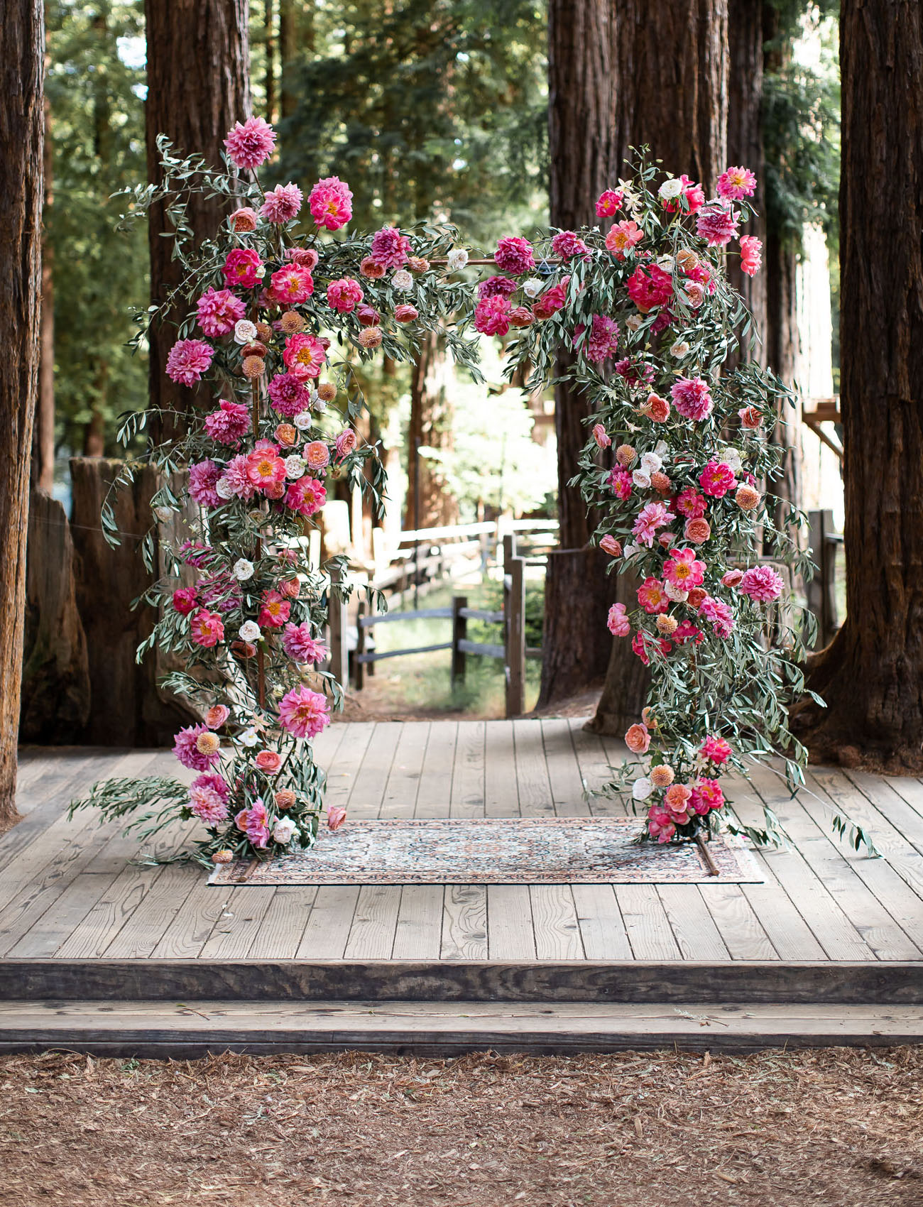 The wedding arch was done with lush greenery and bold blooms in fuchsia and pink plus deep reds