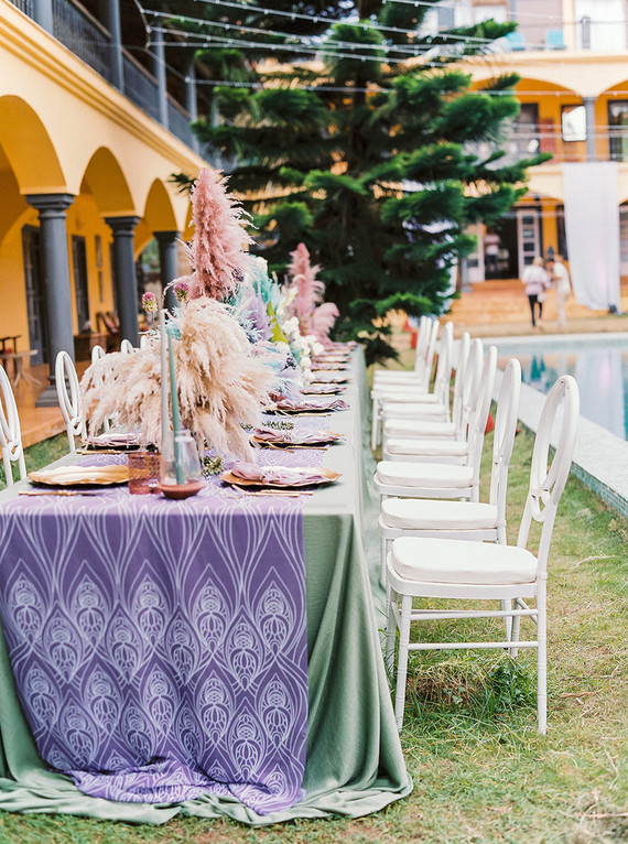 The wedding boho tablescapes were done in green and purple, with dried herbs and leaves, with candles and metallics