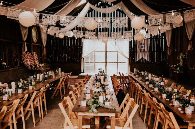 The wedding reception space was done with doilies, paper lanterns, eucalyptus table runners, candles and simple and neutral blooms