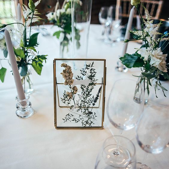 a pressed flower and greenery table number is a very natural and beautiful idea for a spring or summer wedding