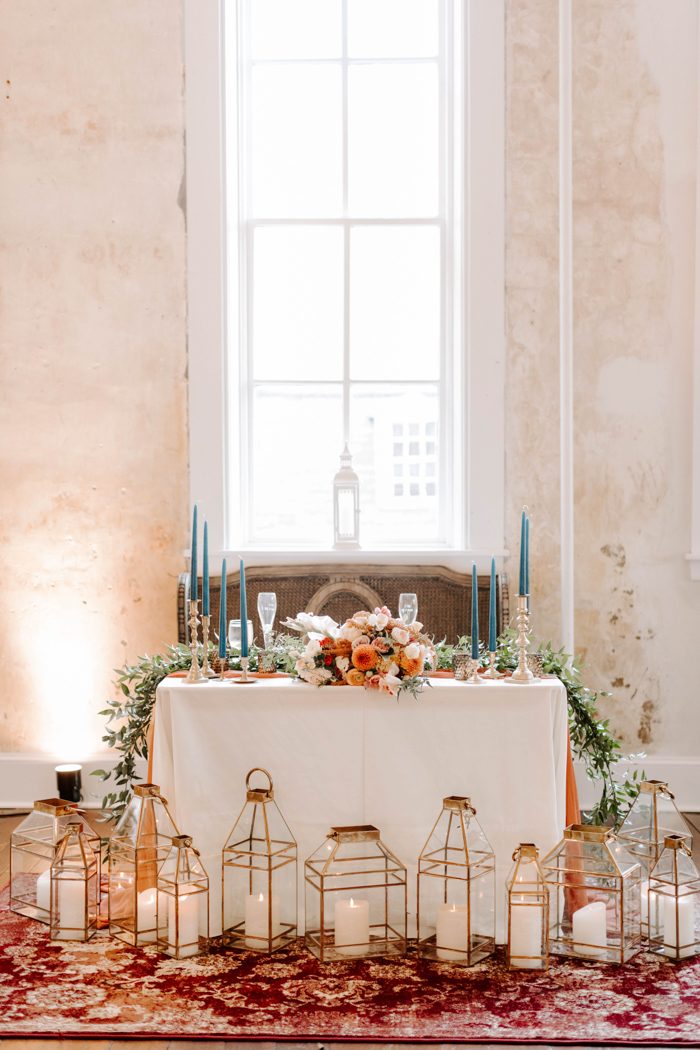 The sweetheart table is accented with lots of candle lanterns and a boho rug