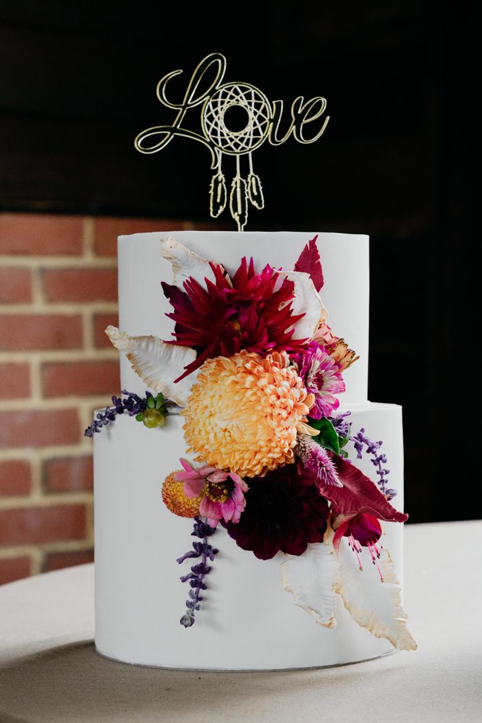 The wedding cake was a white one, with bright blooms and a dream catcher topper