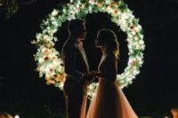 12 a mini round wedding arch fully made of greenery and blooms and lights inside it plus candles all around for a night ceremony