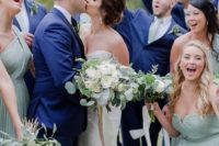 12 groomsmen wearing navy suits and sage green ties and bridesmaids wearing sage green strapless dresses