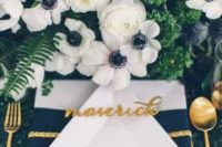 15 a bright and chic tablescape with lush greenery and white blooms, a navy and white napkin and a green sequin tablecloth plus gold cutlery