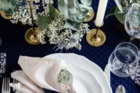 17 a chic table setting with a navy quilted tablecloth, pale greenery and white blooms, tall candles and white porcelain