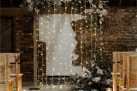23 a wedding backdrop with lights and lush florals and greenery creates a romantic and welcoming ambience in the ceremony space