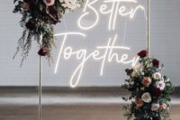 25 a chic wedding arch of metal, with lush blooms and greenery and a neon sign for a modern wedding