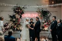 27 a fantastic wedding ceremony space with lots of candles, lush blooms and greenery and a neon sign