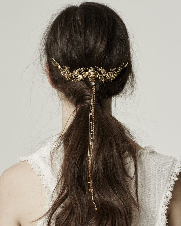 a messy low ponytail with a gold floral hair vine with long chains and rhinestons