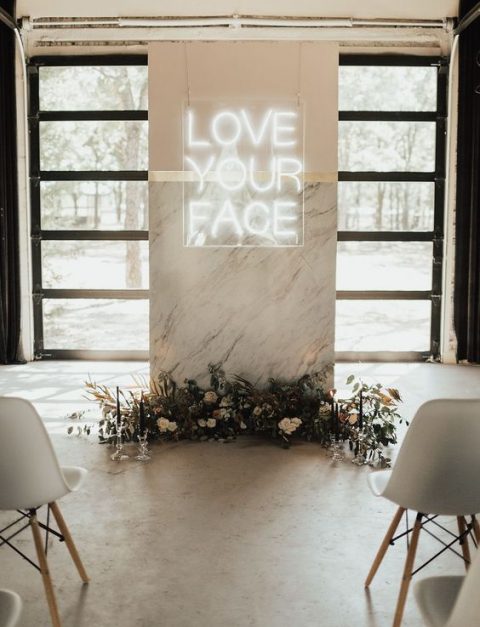 a minimalist wedding ceremony space done with a marble altar decorated with dried leaves, blooms and a neon sign